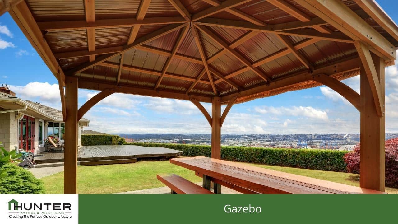 Wooden gazebo overlooking scenic backyard and city view.