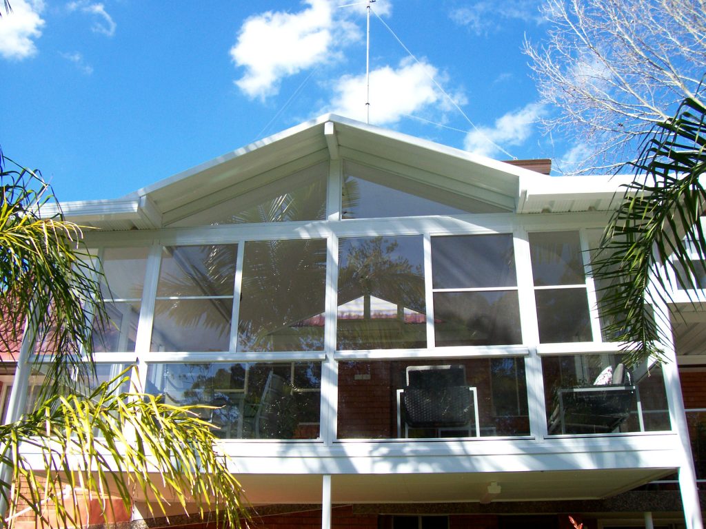 Modern sunroom with large glass windows and roof.