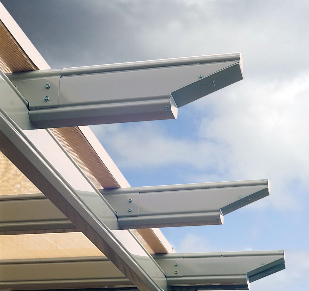 Close-up of modern pergola beams against cloudy sky.