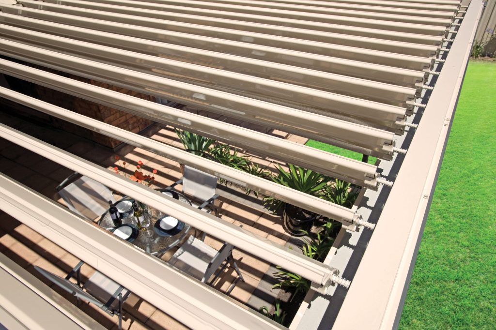 Slatted pergola above patio dining area and garden.