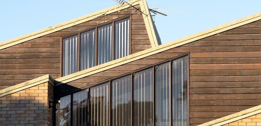 Modern house with sloped roof and large windows.