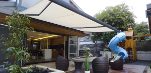 Modern patio with seating, awning, and playground slide.